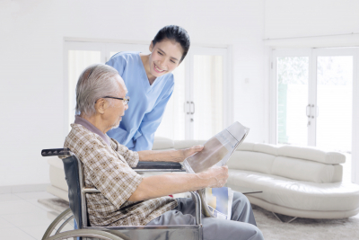 senior man reading newspaper with his caregiver